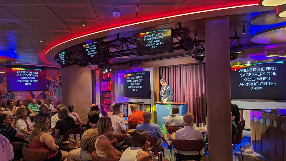Cruise Entertainer running a Cruisa Trivia game on Wonder of the Seas as guest contestants watch