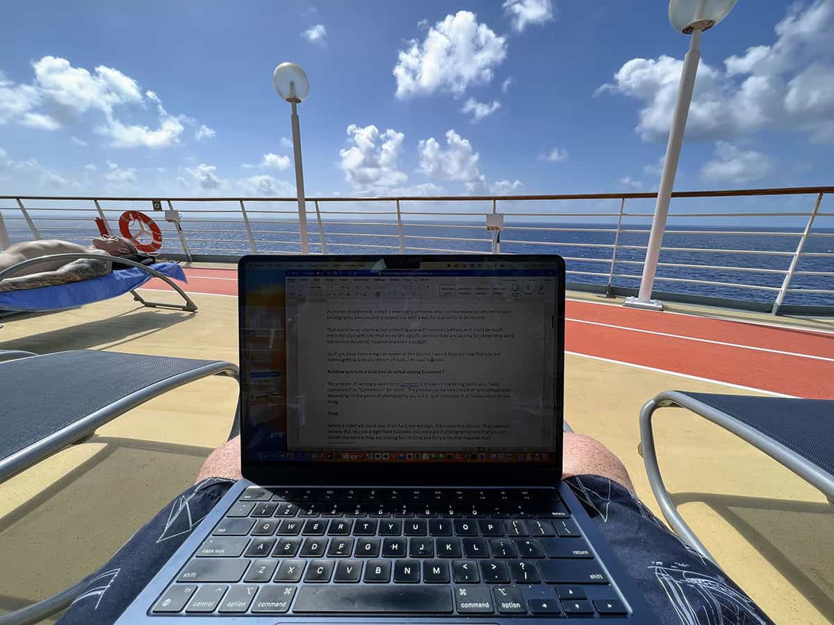 Man sitting with laptop on lap while sun-bathing on a cruise ship deck