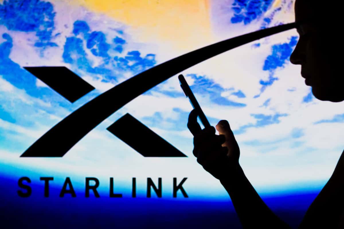 Starlink Internet Logo with silhouette of a person holding phone and image of the Earth in the background.
